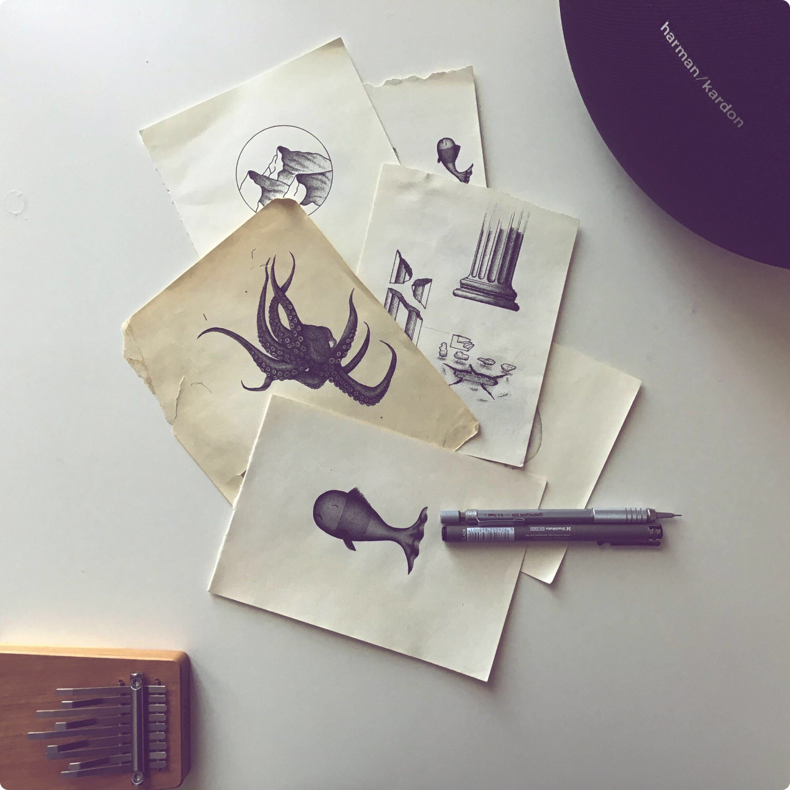 Hand-drawn illustrations on paper beside a pen